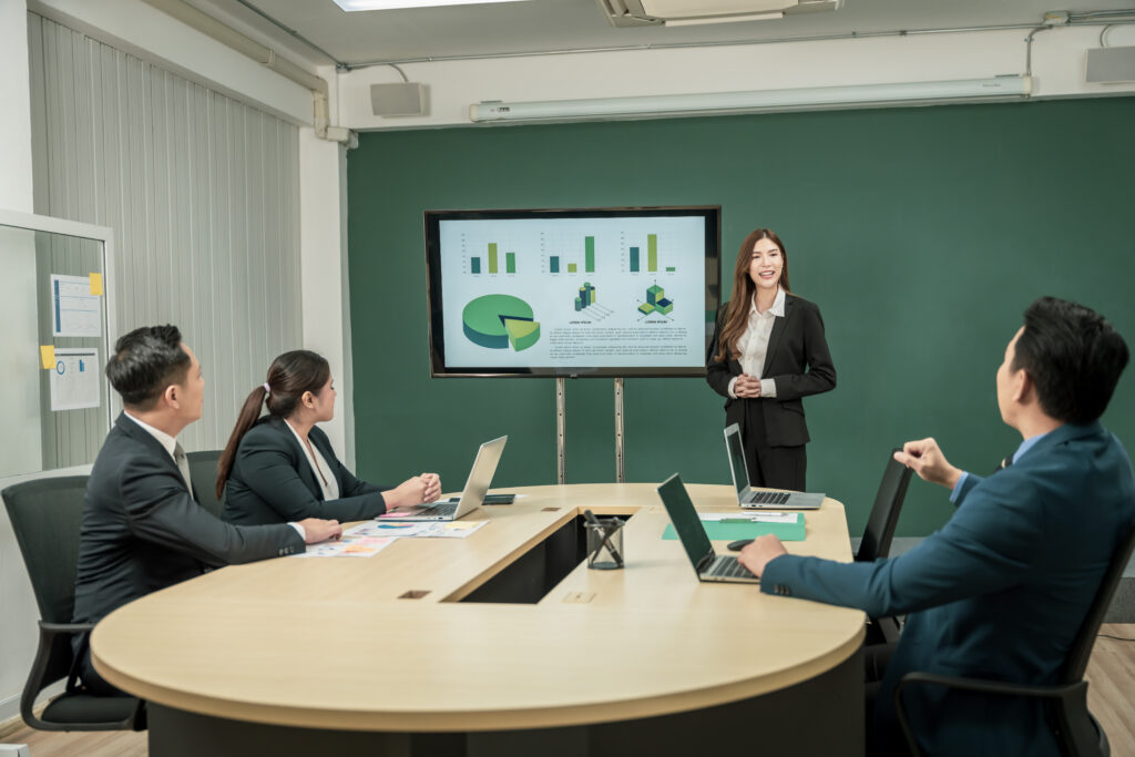 A business professional presenting to her clients in a boardroom.
