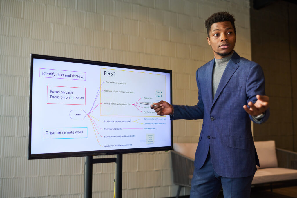 A young business professional delivering a presentation to his peers in a minimalist office setting.